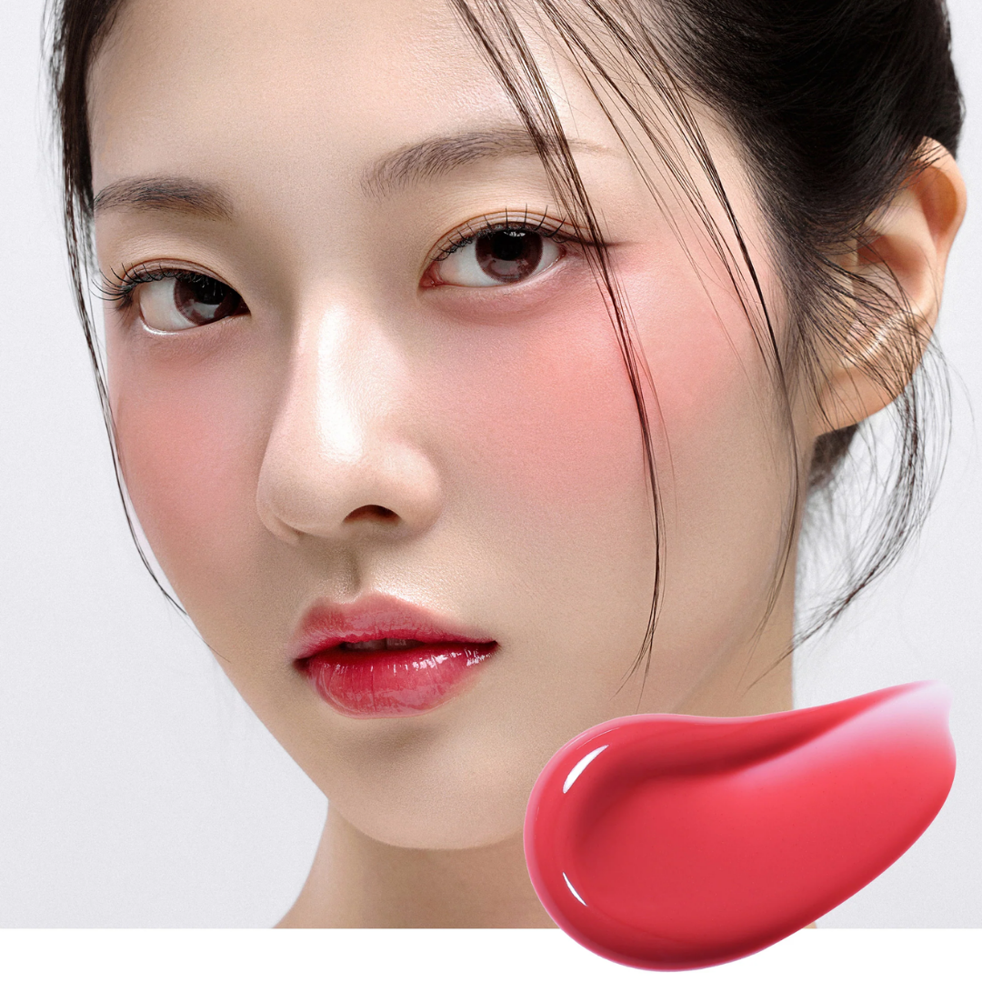 Close-up of a woman's face with pink blush and glossy pink lips, alongside a bright pink product swatch in the lower right corner on a light gray background.